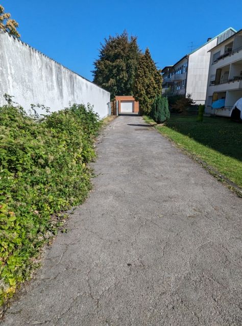 Blick auf Verkaufsobjekt und Nachbarbebauung - Befestigte Zufahrt zwischen Wohnhäusern in einem Wohngebiet