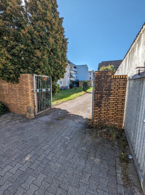 Blick auf die Verkaufsfläche und die Umgebung - Befestigte Zufahrt zwischen Wohnhäusern in einem Wohngebiet