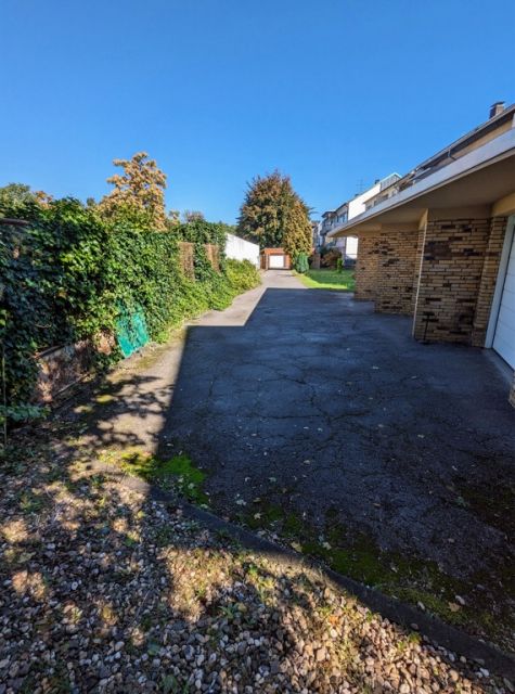 Blick auf die Verkaufsfläche und Nachbarbebauung - Befestigte Zufahrt zwischen Wohnhäusern in einem Wohngebiet