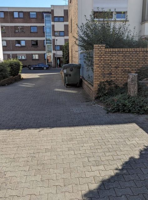 Blick auf das Verkaufsobjekt und die Umgebung - Befestigte Zufahrt zwischen Wohnhäusern in einem Wohngebiet