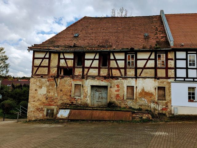 Blick auf Verkaufsobjekt und Nachbarbebauung - Teil einer ehemaligen Wassermühle in zentraler Lage am Kirchplatz mit Garagenzeile