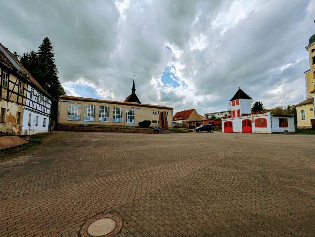 Blick auf Verkaufsobjekt links und die Umgebung - Teil einer ehemaligen Wassermühle in zentraler Lage am Kirchplatz mit Garagenzeile