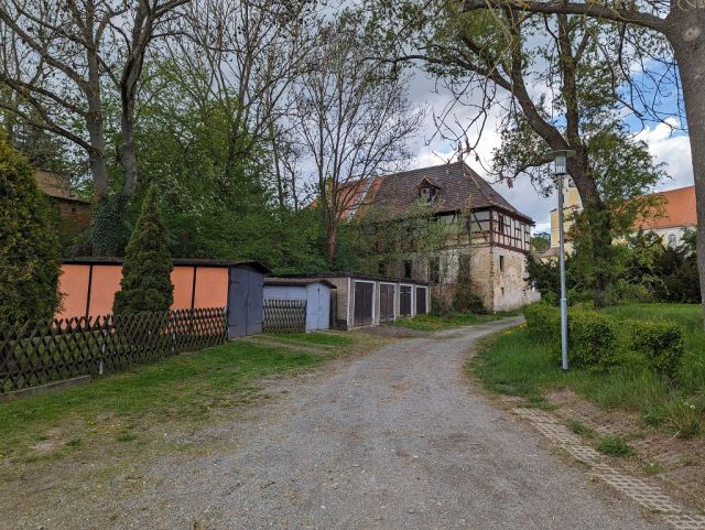 Blick von der Burgstraße auf Verkaufsobjekt und die Umgebung - Garagenzeile und Teil einer ehemaligen Wassermühle in zentraler Lage am Kirchplatz