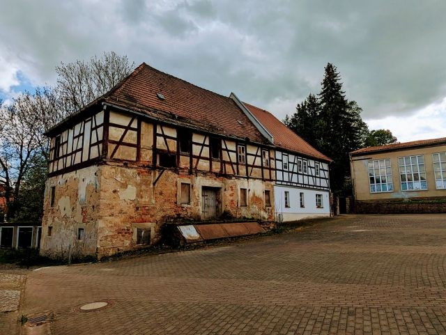 Blick auf Verkaufsobjekt und Nachbarbebauung - Garagenzeile und Teil einer ehemaligen Wassermühle in zentraler Lage am Kirchplatz