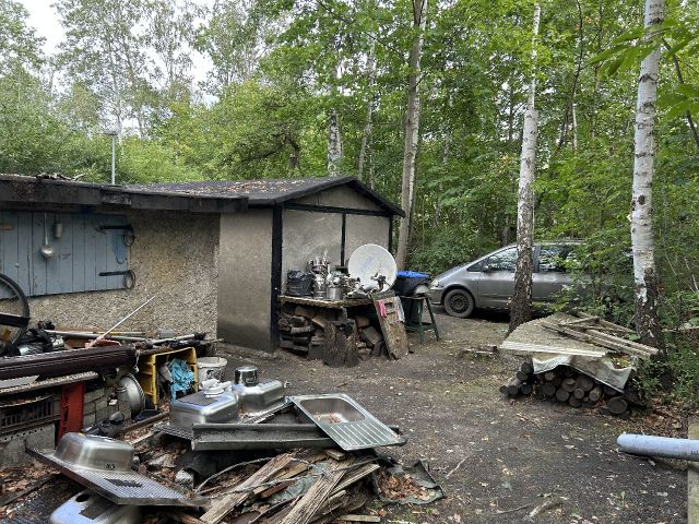 Blick auf Verkaufsfläche mit Ablagerungen und Nachbargrundstück vorn - Innenbereichsgrundstück mit Garage in ruhiger Wohnlage im Lausitzer Seenland